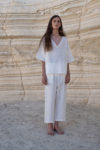 Model standing in a minimalist backdrop wearing a white unisex linen shirt with wide sleeves