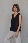 Model showcasing the V-Neck Linen Sleeveless Blouse in a modern, minimalist setting, highlighting its versatile style