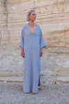 A model lounging while wearing the natural linen Galabeya dress for a relaxed look.