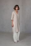 Side view of V-neck linen tunic RONA in ivory color, showcasing its high-low hem, side slits, and tailored 2/3 sleeves made from medium-weight linen.