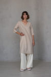 Full-length front view of the V-neck linen tunic RONA in ivory, paired with linen pants, highlighting the relaxed yet elegant fit, high-low hemline, and side slits for effortless sophistication.