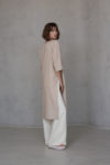 Back angle of the V-neck linen tunic RONA in elegant ivory, highlighting the flowing high-low hem and subtle side slits for a refined and versatile look.