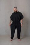 Men’s linen jumpsuit SIGMA in black, featuring a loose top, hidden buttons, waist tie, side pockets, and elastic cuffs for a relaxed yet tailored look.