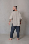 Back view of the relaxed linen top showcasing its clean lines, breathable fabric, and high-low hem in natural flax color.