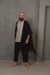 A man posing with the black DUKAY linen jacket flowing, highlighting its open weave and one-size-fits-all fit.